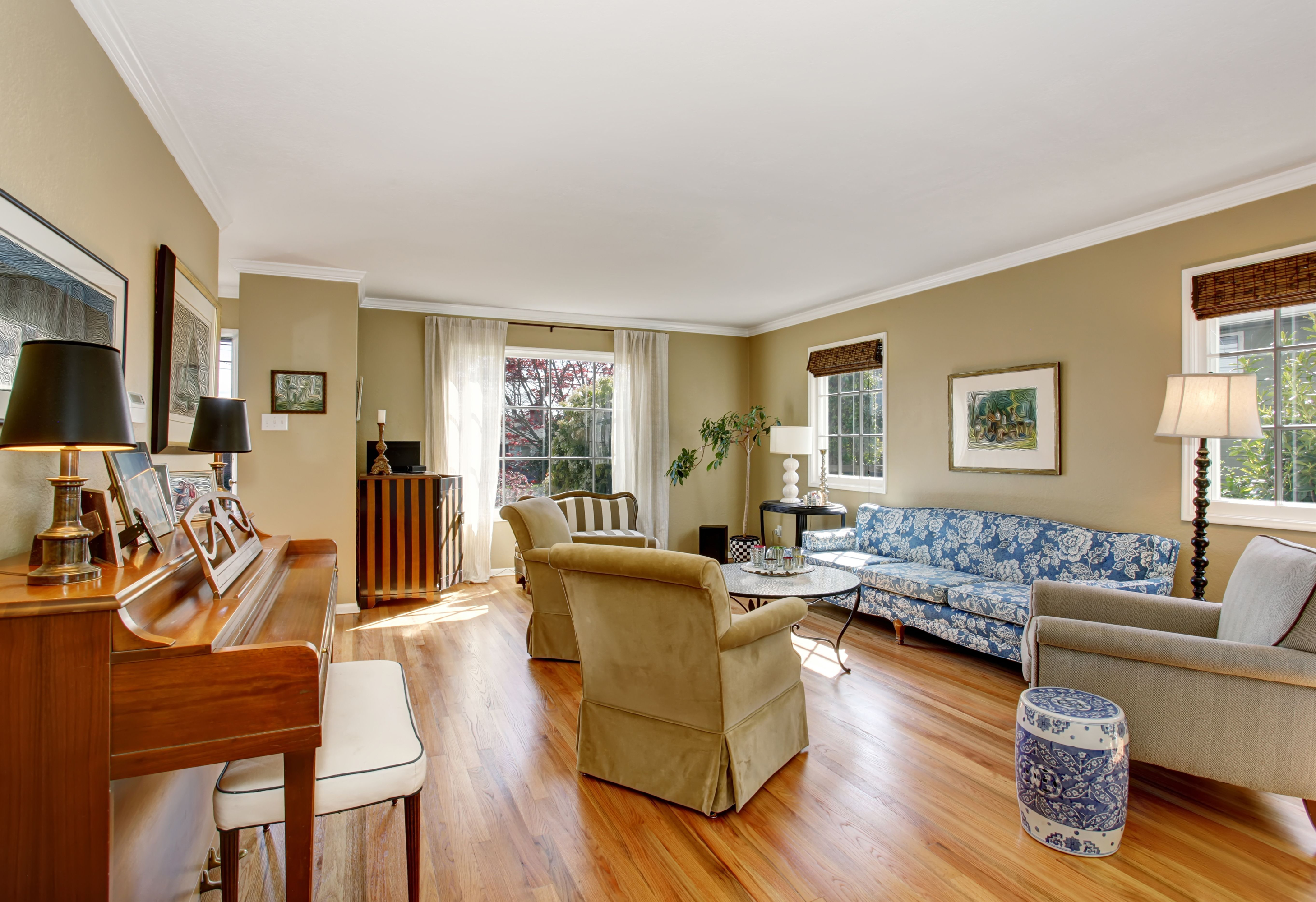 Classic living room with grand piano and rolled up woven wood shades